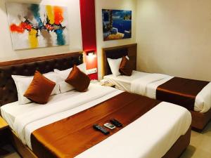 two beds in a hotel room with two remote controls at Grandeur By Avion Palace Near T2 International Airport in Mumbai