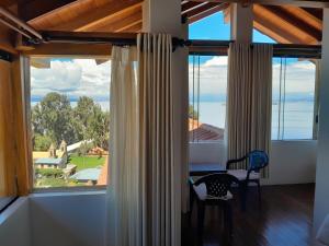 Cette chambre dispose d'une grande fenêtre avec une table et des chaises. dans l'établissement CASA DE LA LUNA-Isla del sol Bolivia, à Comunidad Yumani