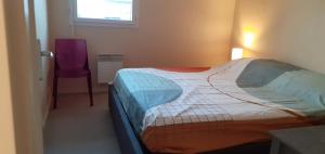 a bedroom with a bed and a purple chair at Appartement avec grand balcon sud et parking privé in Saint-Brieuc