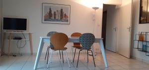 a dining room table with chairs and a television at Appartement avec grand balcon sud et parking privé in Saint-Brieuc