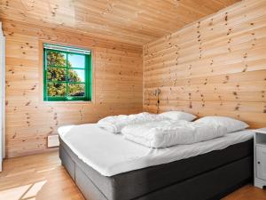 uma cama num quarto de madeira com uma janela em Holiday home Tjørhom II em Tjørhom
