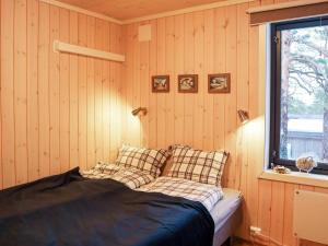 een slaapkamer met een bed met kussens en een raam bij Holiday home Risør in Risør