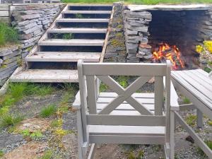 een houten bank naast een vuur bij Holiday home Melfjordbotn 