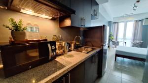 cocina con fregadero y microondas en The French Apartment Pasig - Fast Wi-Fi and pool en Manila
