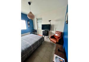 1 dormitorio con 1 cama, 1 silla y TV en Chambre tropicale privée, en Liévin