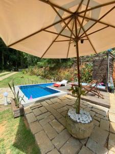 a large umbrella sitting next to a swimming pool at Ônibus Azul - Experiência de Hospedagem em Domingos Martins in Domingos Martins