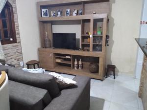 a living room with a couch and a flat screen tv at Cantinho da Margarete in Santa Cruz Cabrália