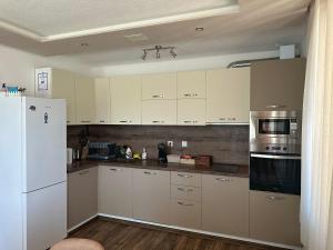a kitchen with white cabinets and a white refrigerator at Къща за гости "СЛАВЕНА" in Dospat