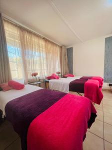 a hotel room with three beds with red blankets at Ditoro Boutique Hotel in Pretoria