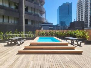 a swimming pool on a rooftop with two picnic tables and benches at Smart, Contemporary Designed Apartment in Cape Town