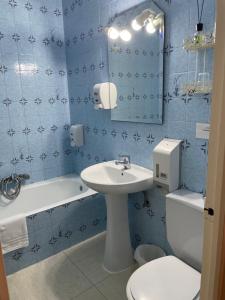 baño de azulejos azules con lavabo y aseo en Hostal Ochoa, en San Adrián