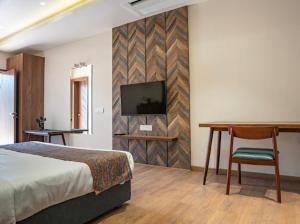 sypialnia z łóżkiem, biurkiem i telewizorem w obiekcie Casa Oro w mieście Ujjain