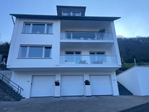 a white house with three garage doors and stairs at Gästehaus Paulina in Cochem