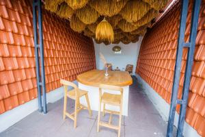 una mesa y sillas en una habitación con una pared de color naranja en Shortcut Breeze Guest House, en Canggu