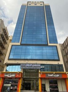a tall building with blue windows in a city at فندق ملتقي الإيمان للضيافة السياحي in Mecca