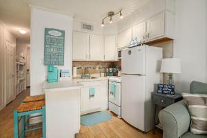 a kitchen with white cabinets and a white refrigerator at Tipsea on the seawall in Galveston