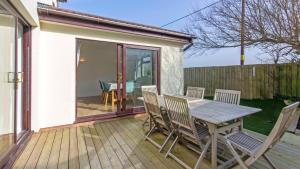 a wooden deck with a wooden table and chairs at Rockpool - Attractive and spacious retreat near Croyde beach - Sleeps 8 in Croyde