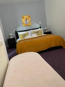 3 bedroom flat in Maida Vale في لندن: غرفة نوم بسريرين مع شراشف صفراء