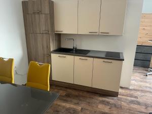 a kitchen with a sink and two yellow chairs at Eisenstrassen Apartment in Ybbsitz