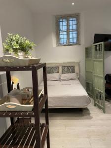 ein kleines Schlafzimmer mit einem Bett und einem Regal mit Blumen in der Unterkunft Apartamentos Cuna 21 in Sevilla