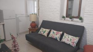 ein schwarzes Sofa mit drei Kissen im Wohnzimmer in der Unterkunft Apartamentos Cuna 21 in Sevilla