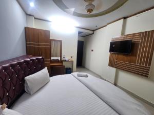 Hotel S.A International في كوكس بازار: غرفة نوم مع سرير وتلفزيون على الحائط