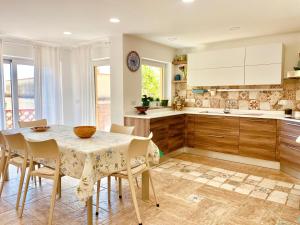 una cocina con mesa y sillas y una cocina con armarios blancos. en La Casa di Alessandro, en Giardini Naxos