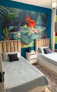 a bedroom with two beds and a mural at Villa in a compound with a rooftop in sheikh zayed in Sheikh Zayed
