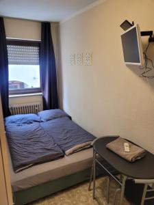 um pequeno quarto com uma cama e uma mesa em MB City Pension em Nurembergue