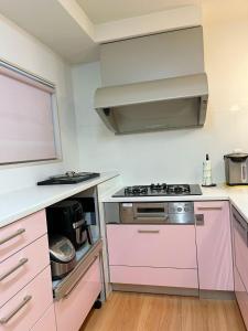 豐中的住宿－Otami Stay，粉红色的厨房配有炉灶烤箱