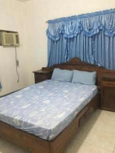 ein Schlafzimmer mit einem Bett mit einem blauen Vorhang und einem Fenster in der Unterkunft Crossroads Beach House in Sablayan