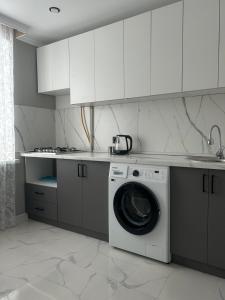 a white kitchen with a washing machine in it at Уютная квартира в центре города in Aktobe