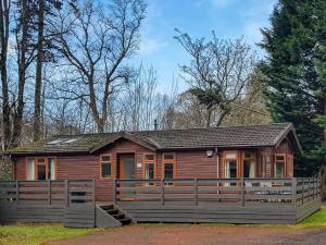 una baita di tronchi con una recinzione di fronte ad essa di Loch Lomond Sanctuary Lodges a Balloch