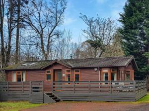 a log cabin with a fence in front of it at Loch Lomond Sanctuary Lodges in Balloch