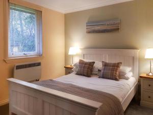 1 dormitorio con 1 cama con 2 lámparas y una ventana en Loch Lomond Sanctuary Lodges, en Balloch
