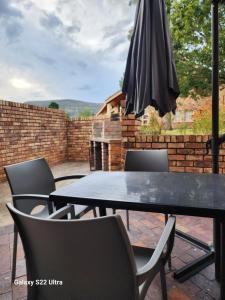 Una mesa con sillas y una sombrilla en un patio. en Aurora Inn Clarens, en Clarens