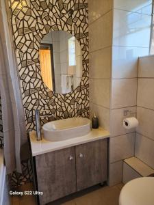 un baño con lavabo y espejo en Aurora Inn Clarens, en Clarens 24 fotos más