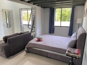 a bedroom with a bed and a couch and windows at Homestay Studio TOKAYOH in Kota Bharu