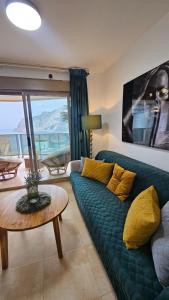 a living room with a green couch and a table at Esmeralda Suites Sunrise in Calpe