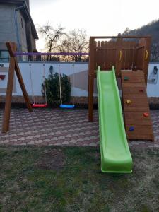 un parque infantil con un tobogán verde en un patio en Cabana BRO Clisura Dunarii en Liborajdea