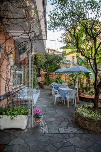 un patio con mesas, sillas y una sombrilla en Albergo La Marinella, en Varazze