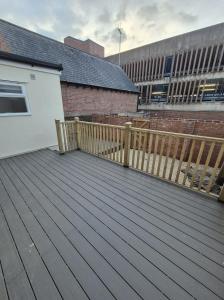 a wooden deck with a fence and a building at Modern 1 Bedroom Apartment in Central Cheltenham 