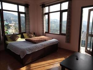 1 dormitorio con 1 cama con ventanas y mesa en Hotel Thakur Home's Mountain View - Outdoor furniture - Picnic Area, en Jutogh