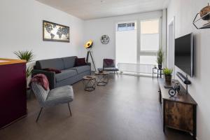 a living room with a couch and a tv at Casa Milla, Apartment Wuhr - Zentrales Loft am Fluss inklusive Parkplatz in Langenthal