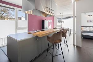 une cuisine avec des murs roses et un comptoir avec des tabourets dans l'établissement Casa Milla, Apartment Langenthal, à Langenthal