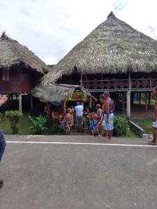 un grupo de personas de pie fuera de una cabaña en Hospedaje Agroturismo Wounaan, en Pidiaque