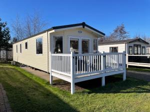 una piccola casa gialla con portico e una casa di Seton Sands Haven Holiday Park - Prestige Caravan a Port Seton