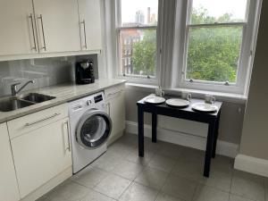 uma cozinha com uma máquina de lavar roupa e uma mesa em Falcon Baker Street Apartment em Londres