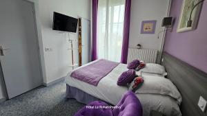 a bedroom with a bed with purple pillows on it at Hôtel Le Rohan Charme et Caractère in Pontivy