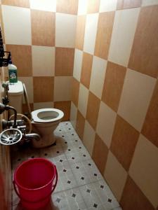 ein Badezimmer mit einem WC und einem roten Eimer in der Unterkunft soms estate stay in Madikeri
